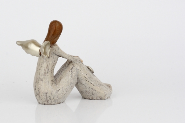 Anděl sedící se zlatými křídly a srdcem 