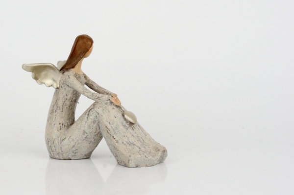 Anděl sedící se zlatými křídly a srdcem 